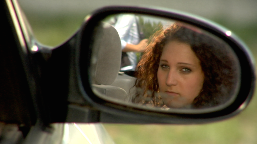 Woman reflected in car side mirror