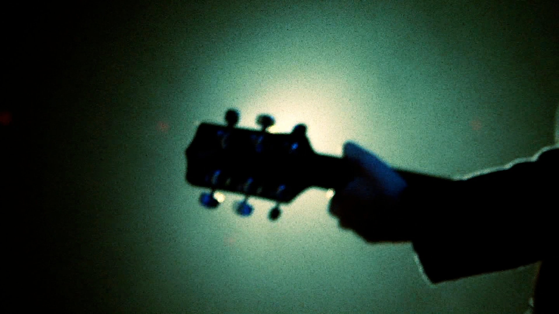 Guitar headstock silhouette against teal light